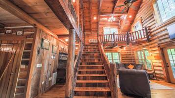 A wooden staircase leading to a balcony with a view, a sofa, and a fireplace.