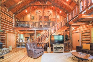 A spacious log cabin interior with a large staircase, a leather recliner, a flat-screen TV, and a cozy seating area. - Lakeside Cabin - 2 Fireplaces-hot Tub Sauna Games (Mars Hill)