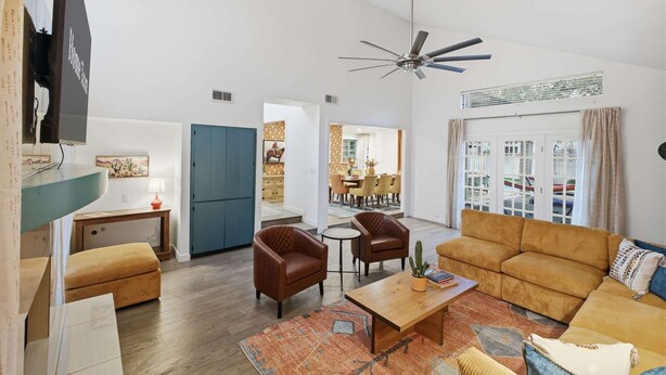 Una sala de estar moderna con un sofá, sillones, una mesa de centro y un ventilador de techo.