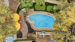 Piscina rodeada por una terraza con asientos y un pequeño jardín.