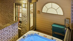 Un jacuzzi en un rincón, con pared de ladrillo y ventana.