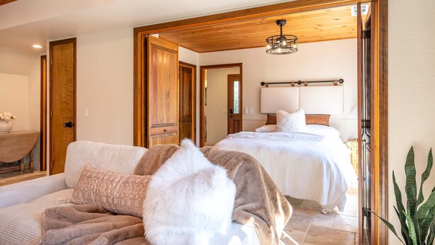 A bedroom with a large bed, a smaller sofa, and a wooden ceiling. - Sequoia Getaway Private Pool Sauna (Three Rivers)