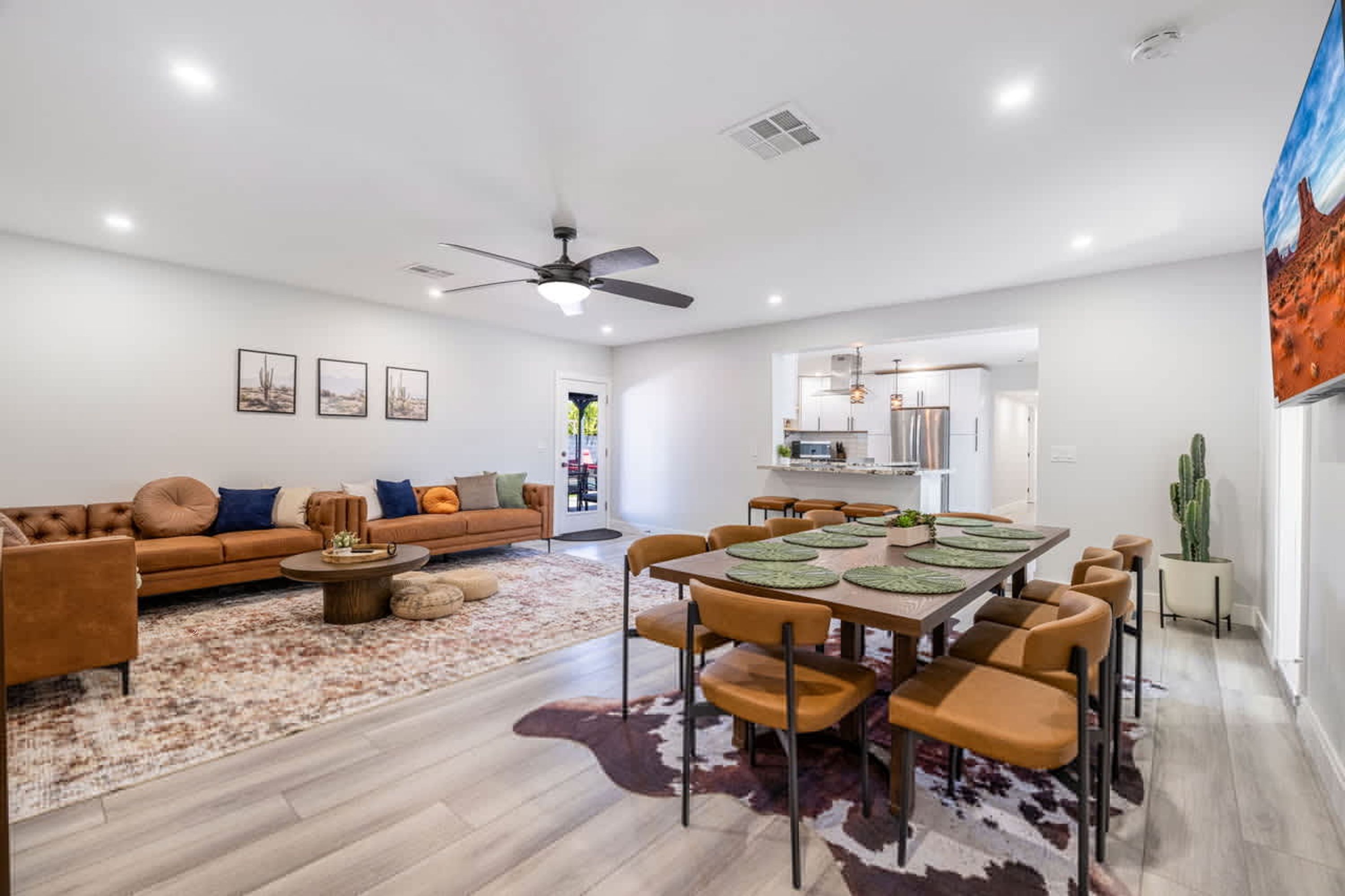 A spacious living room with a modern sofa, a dining table with chairs, and a kitchen in the background.