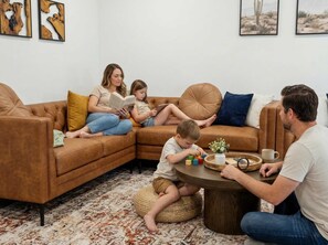 Eine Familie in einem Wohnzimmer mit einem braunen Ledersofa, einem Couchtisch und einem Teppich.