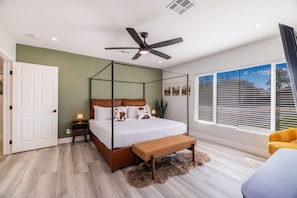 A bedroom with a four-poster bed, a ceiling fan, a large window with blinds, and a wooden bench. - Casa Mesa Private Paradise w Pool Putt Games (Mesa)