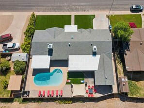 Ein Wohnhaus mit Swimmingpool, überdachter Terrasse und Garage.