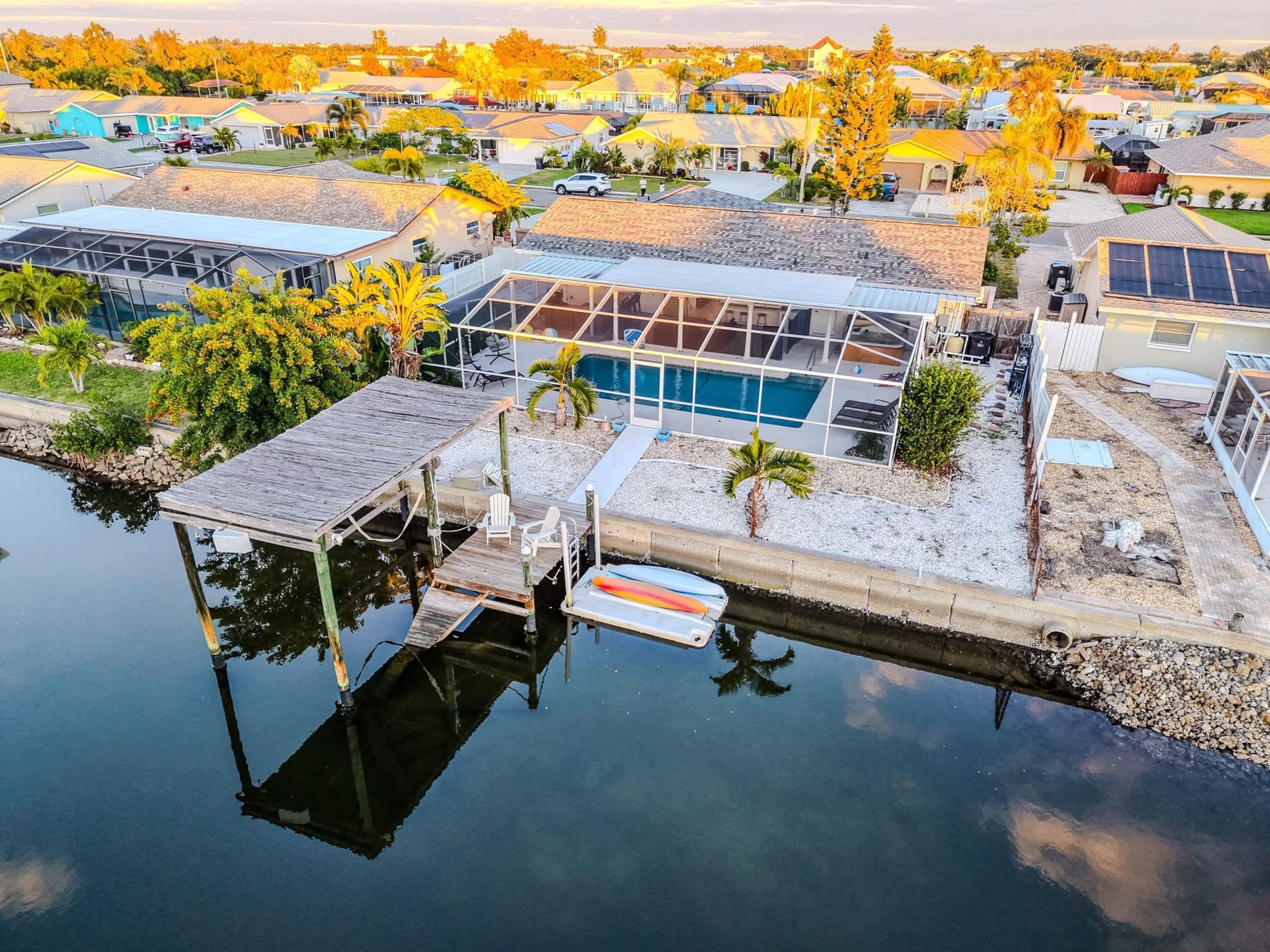 A residential area with a dock, swimming pool, and houses with solar panels.