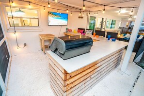 A modern kitchen with a central island, wooden cabinets, and a large window. - Private Dock Heated Pool Hot Tub Game Room Fun (Apollo Beach)