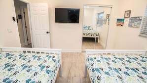 Een kamer met twee bedden, een televisie en een deur naar een andere kamer.