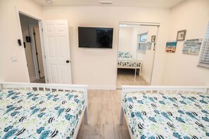 A room with two beds, a television, and a door leading to another room. - Private Dock Heated Pool Hot Tub Game Room Fun (Apollo Beach)