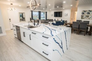 A modern kitchen with a marble island, built-in appliances, and a dining area with a table and chairs. - Private Dock Heated Pool Hot Tub Game Room Fun (Apollo Beach)