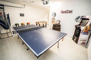 Ein Raum mit Tischtennisplatte, Kicker und einem GameCave-Spielautomaten.