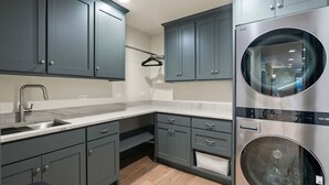 A modern kitchen with grey cabinets, a stainless steel sink, and a built-in washing machine. - Lakeside Montana Hot Tub Game Room (Lakeside)