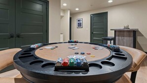A poker table with chips and cards, surrounded by chairs, in a room with doors and a framed picture on the wall. - Lakeside Montana Hot Tub Game Room (Lakeside)