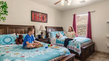 A bedroom with two beds, a ceiling fan, a window with curtains, and a wall-mounted picture.