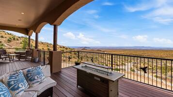 A covered outdoor area with a wooden deck, seating, and a barbecue station.