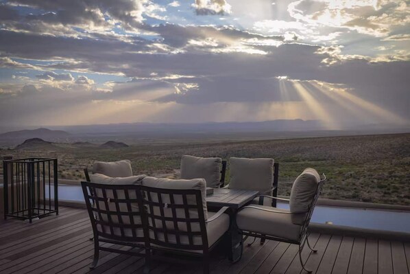 An outdoor deck with a table and chairs, overlooking a desert landscape with mountains in the distance. - Private Estate Pool Views Events Welcome (Las Cruces)