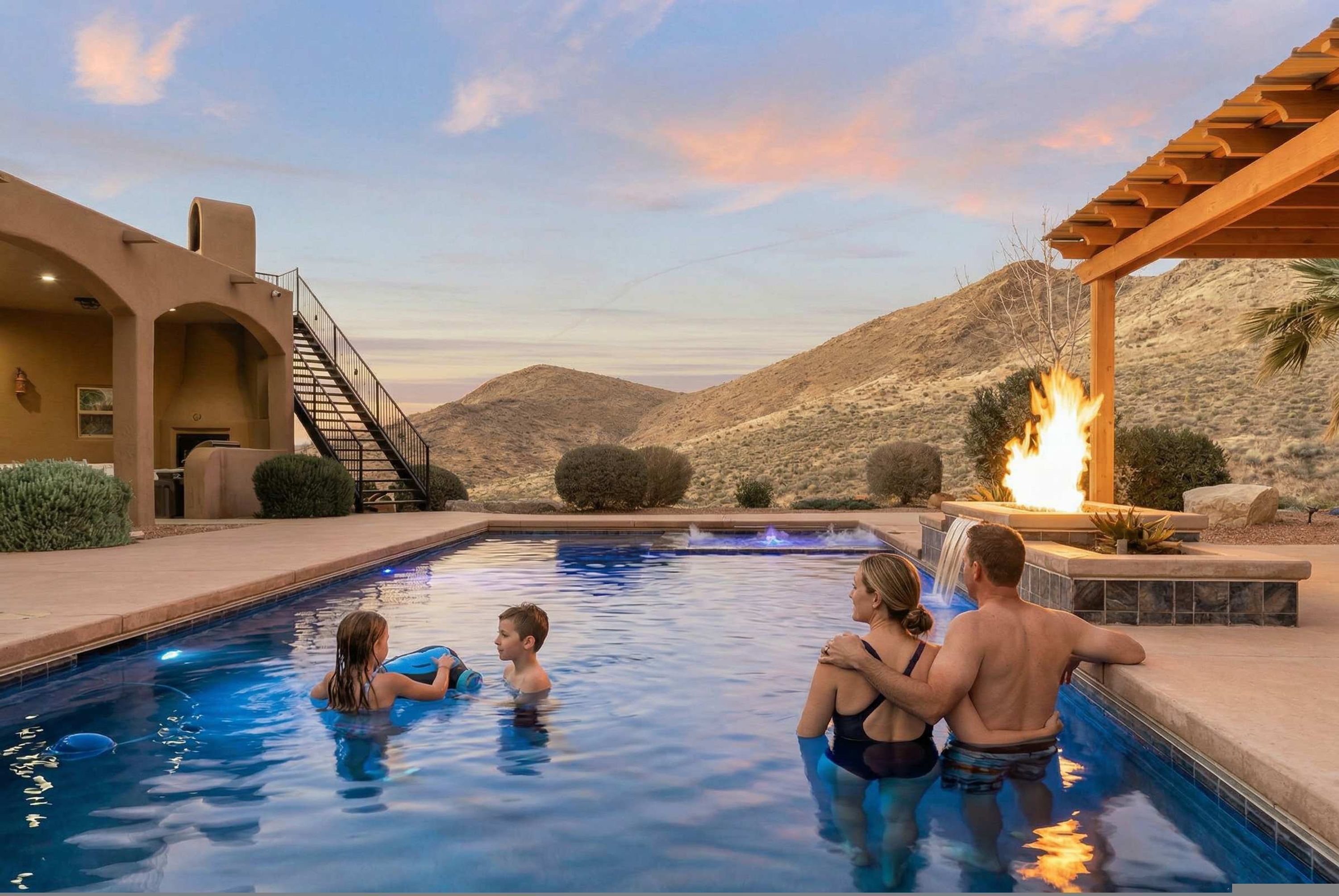 Una piscina con un elemento de fuego, rodeada por un paisaje desértico y un edificio con paseos en arco.