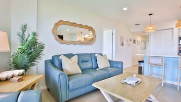Un salon avec un canapé bleu, une table basse en bois et un grand miroir au mur.