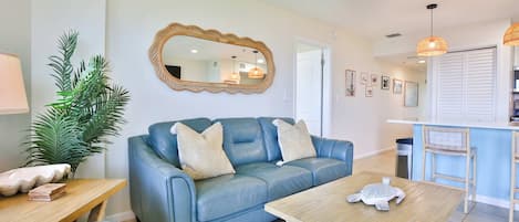 A living room with a blue sofa, a wooden coffee table, and a large mirror on the wall.