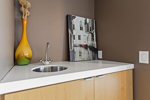 A bathroom with a white countertop, a stainless steel sink, a wooden cabinet, a decorative vase, and a wall-mounted painting. - Mtn Views Sleeps 8 Hot Tub Game Room Fireplace (Blue Ridge)