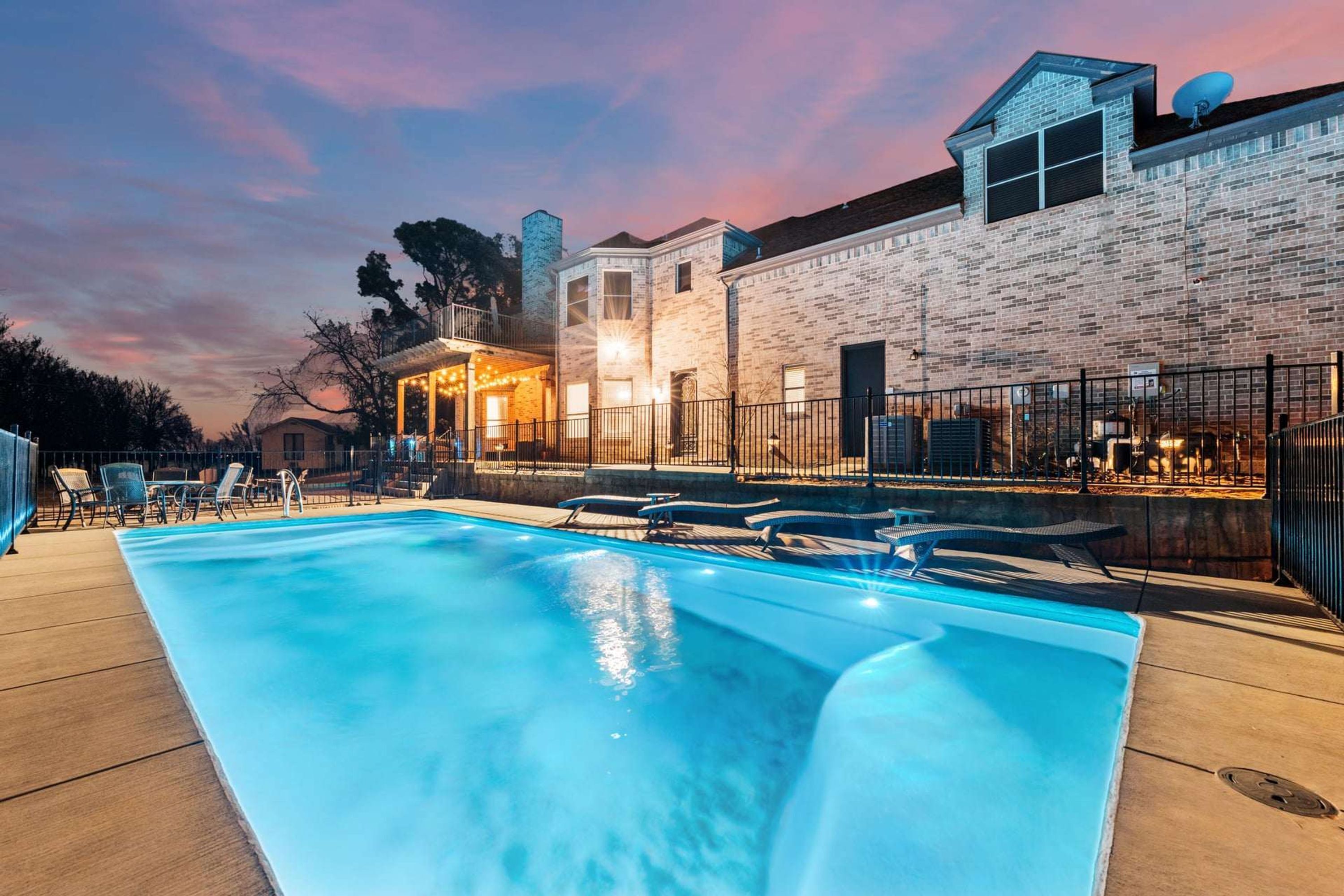 A swimming pool with lounge chairs, a brick building with a satellite dish, and a clear sky.