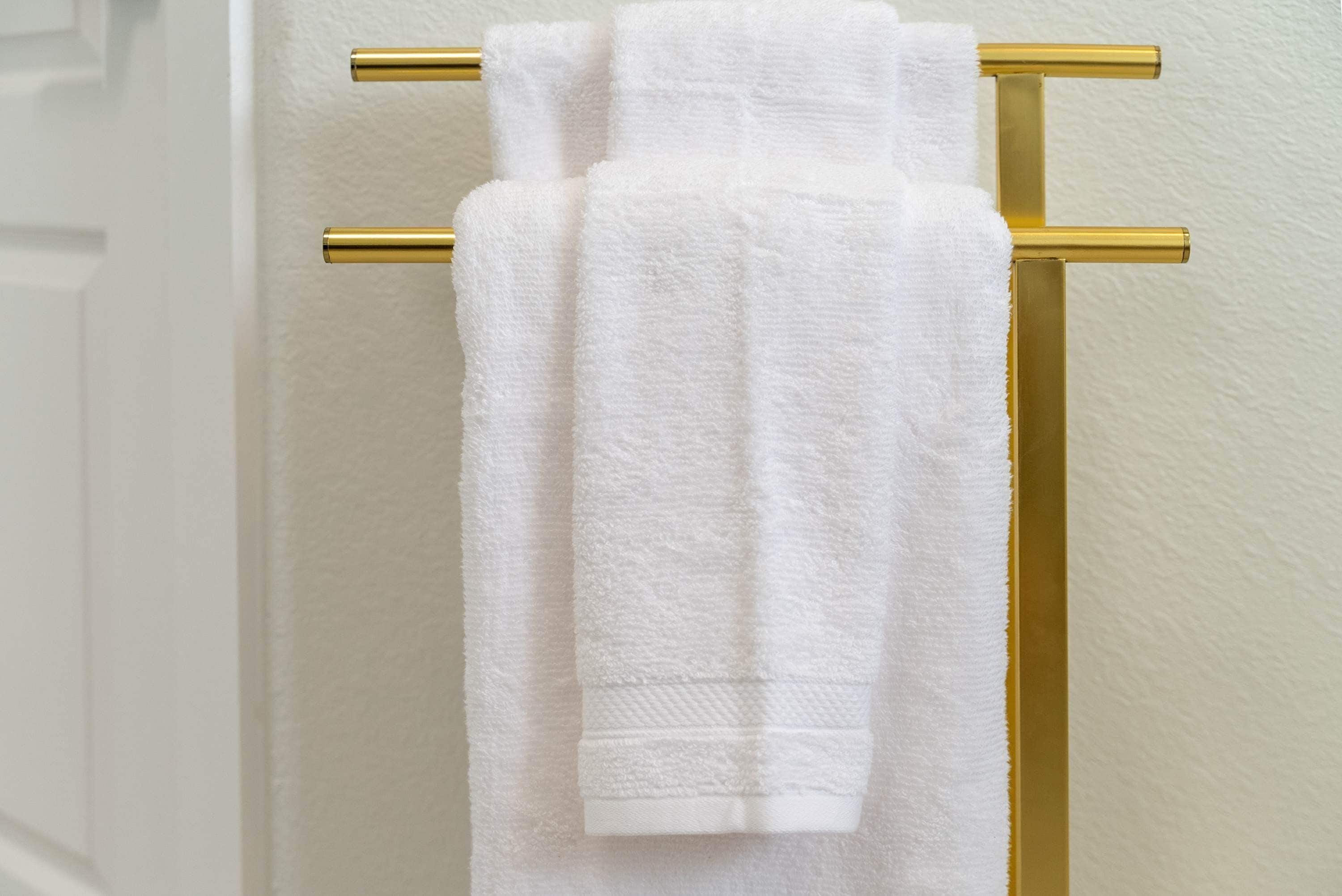 A white towel hanging on a gold towel rack.