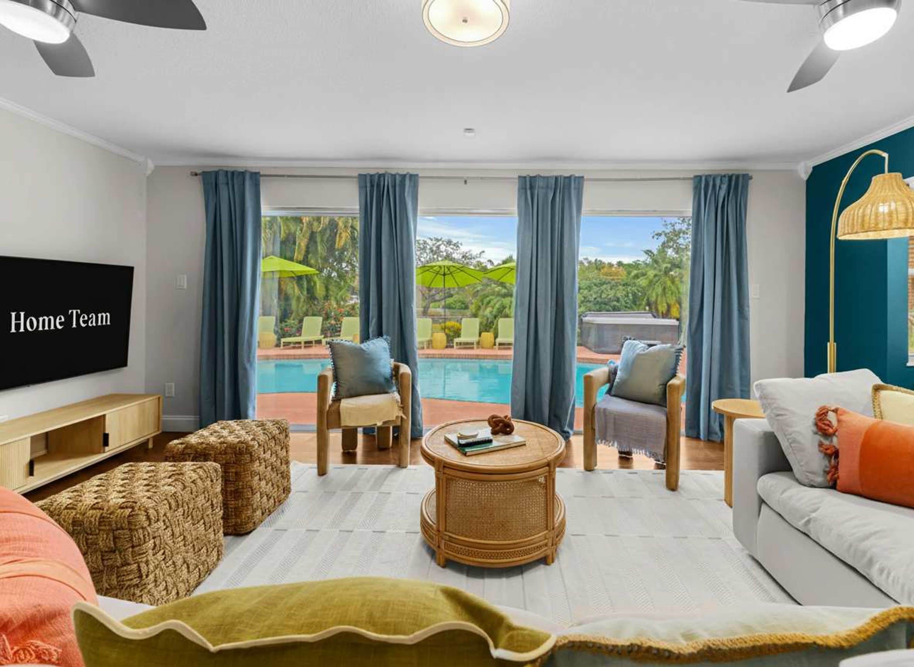 A modern living room with a pool view, a flat-screen TV, and a cozy seating area.