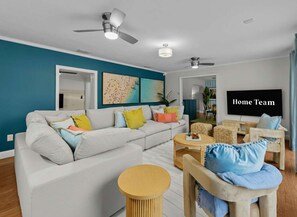 Ein modernes Wohnzimmer mit einer Couch, Sesseln, einem Couchtisch und einem Fernseher.