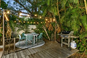 An outdoor patio with a round table and chairs, a barbecue grill, and string lights. - Sleeps 20 Heated Pool Pickleball Hot Tub Fire Pit (Largo)