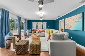 A modern living room with a large sofa, two ottomans, a coffee table, and a ceiling fan. - Sleeps 20 Heated Pool Pickleball Hot Tub Fire Pit (Largo)