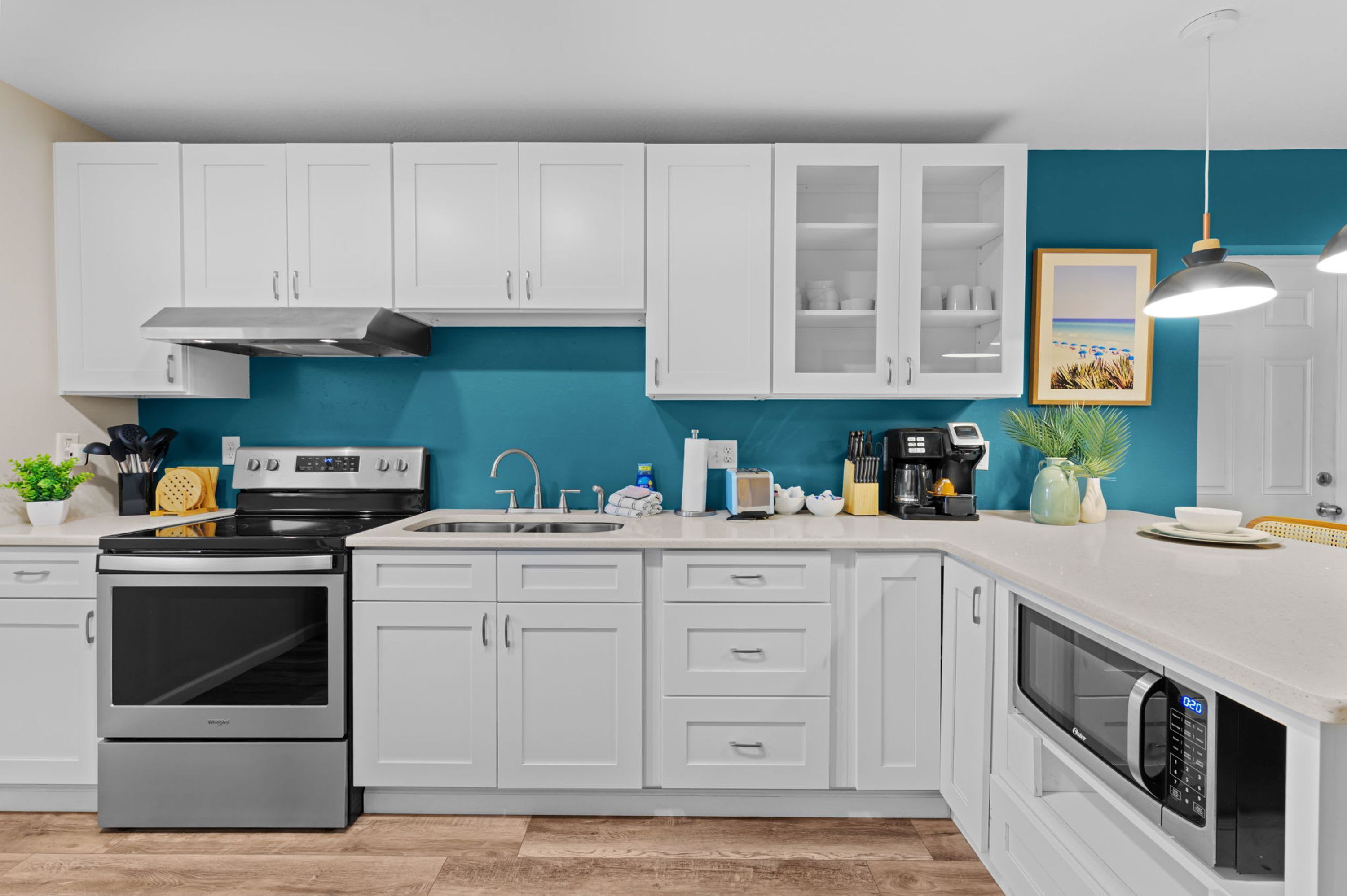 Een moderne keuken met witte kastjes, een roestvrijstalen fornuis en een magnetron.