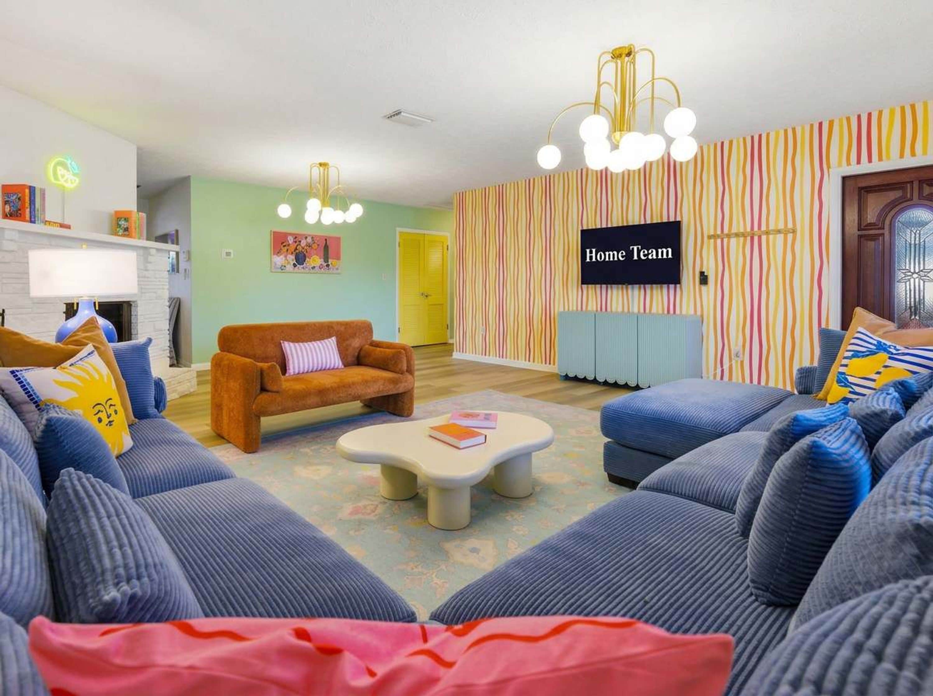 Una sala de estar con un sofá, una mesa de centro, una televisión y un muro a rayas.
