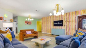 A living room with a sofa set, a coffee table, a television, and a striped wall. - Bradenton Vacation Haven Pool Hot Tub Arcade (Bradenton)