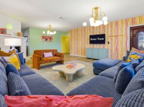 A living room with a sofa set, a coffee table, a television, and a striped wall. - Bradenton Vacation Haven Pool Hot Tub Arcade (Bradenton)
