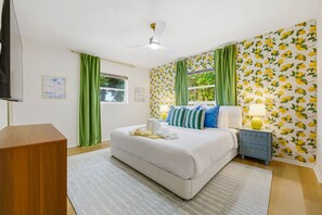 Ein Schlafzimmer mit einem Bett, einem Nachttisch, einer Lampe und einem Fenster mit Vorhängen.