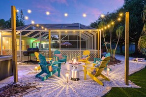 An outdoor patio with a covered seating area, a fire pit, and string lights. - Bradenton Vacation Haven Pool Hot Tub Arcade (Bradenton)