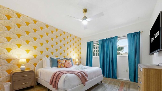A bedroom with a bed, nightstand, and a TV on the wall. - Bradenton Vacation Haven Pool Hot Tub Arcade (Bradenton)