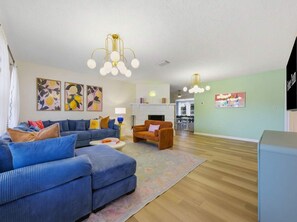 Ein Wohnzimmer mit blauem Sofa, braunem Sessel, Kamin und Fernseher.