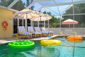 A pool area with lounge chairs, umbrellas, and inflatable floats. - Bradenton Vacation Haven Pool Hot Tub Arcade (Bradenton)