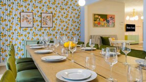 A dining area with a long table set for a meal, surrounded by green upholstered chairs. - Bradenton Vacation Haven Pool Hot Tub Arcade (Bradenton)