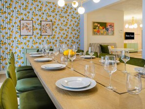 A dining area with a long table set for a meal, surrounded by green upholstered chairs. - Bradenton Vacation Haven Pool Hot Tub Arcade (Bradenton)