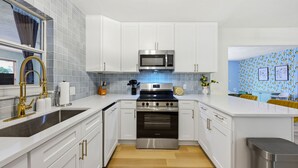 A modern kitchen with white cabinets, stainless steel appliances, and a tiled backsplash. - Bradenton Vacation Haven Pool Hot Tub Arcade (Bradenton)