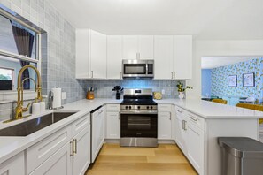 A modern kitchen with white cabinets, stainless steel appliances, and a tiled backsplash. - Bradenton Vacation Haven Pool Hot Tub Arcade (Bradenton)