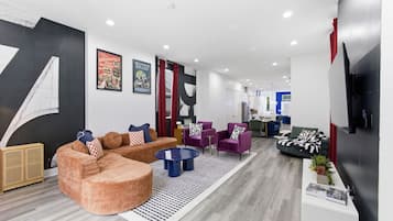 A modern living room with a sofa, armchairs, a coffee table, and a TV.