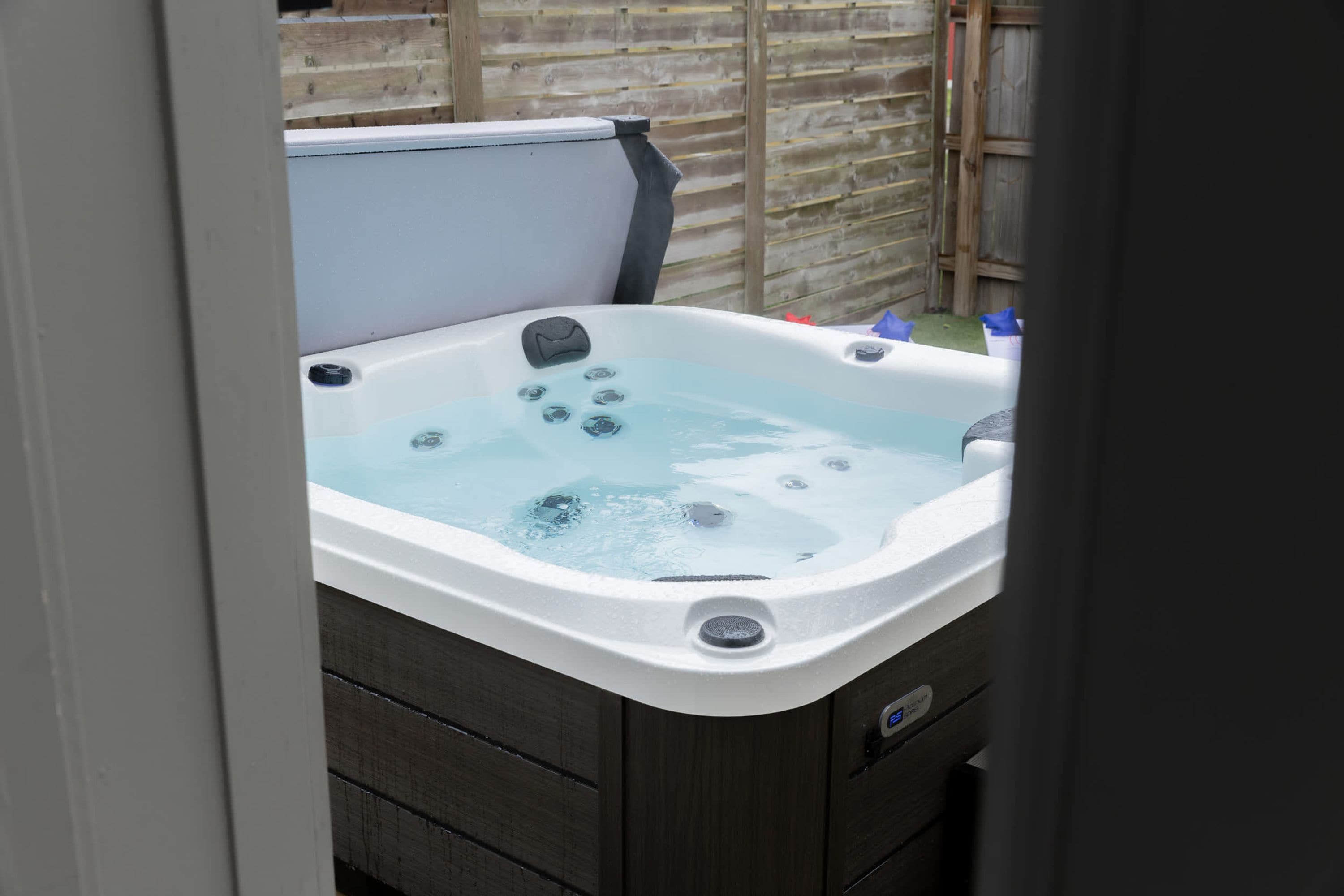 Un jacuzzi con un muelle de madera y una cerca de madera al fondo.