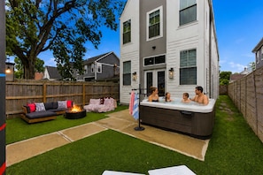 A backyard with a hot tub, a fire pit, and outdoor seating. - Victory Lane Villa Game Room - Hot Tub - Firepit (Indianapolis)