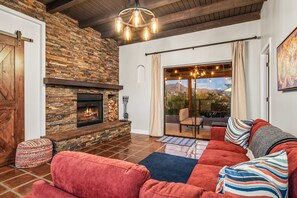 Una sala de estar con chimenea de piedra, un sofá rojo y vistas a través de un ventanal.