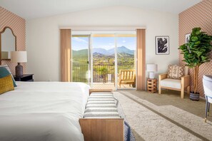 A hotel room with a bed, a chair, a small table, a lamp, a potted plant, and a balcony with a view of the mountains. - 2 Homes 7BR Sleeps 18 Pool Amazing Mtn Views (Tucson)