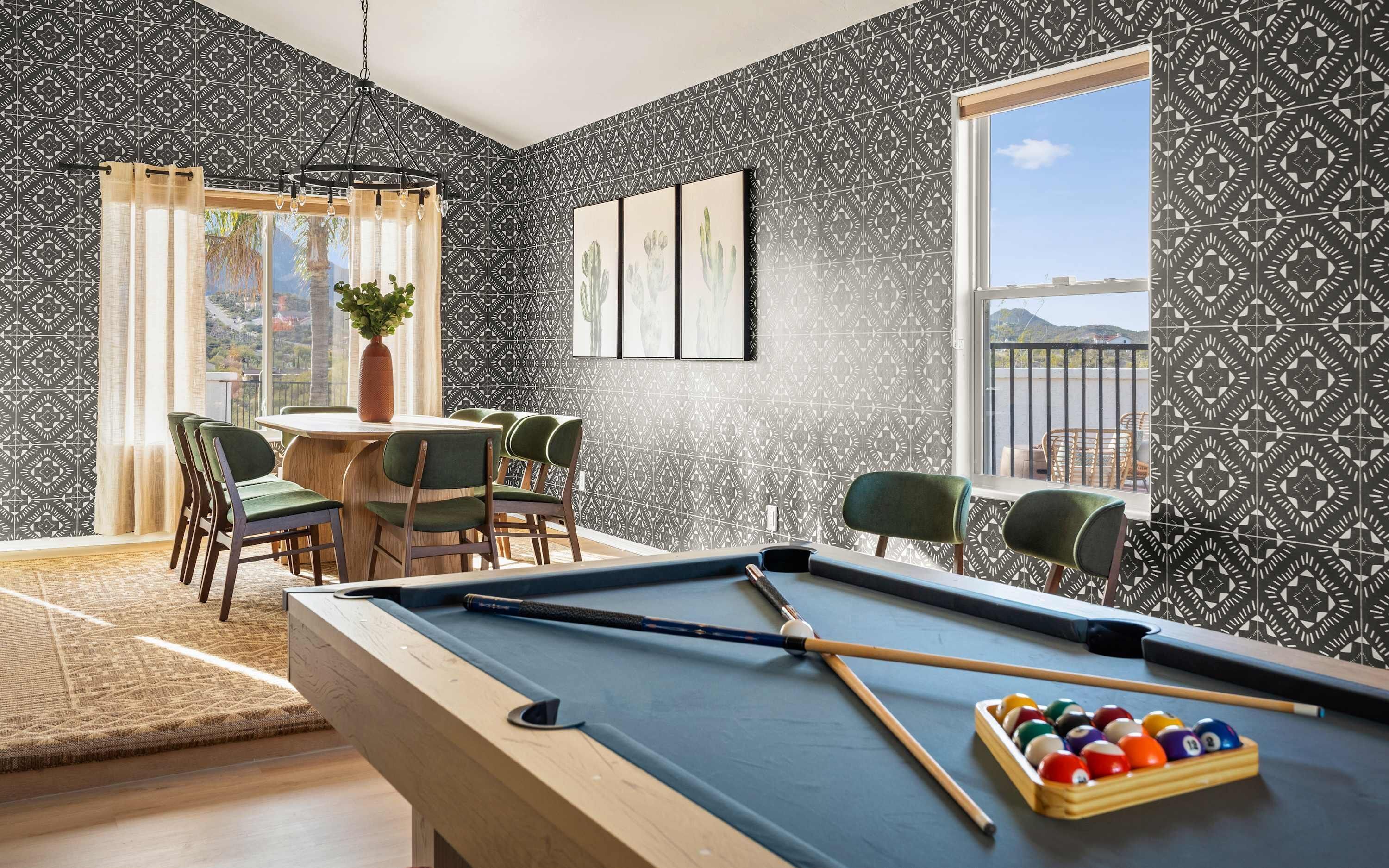 A pool table with a cue stick and balls, a dining area with chairs and a table, and a window with a view.